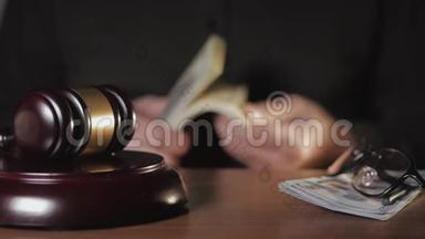 在法庭上贿赂的概念法官的特写`法庭上的锤子。 `的手在数着一个